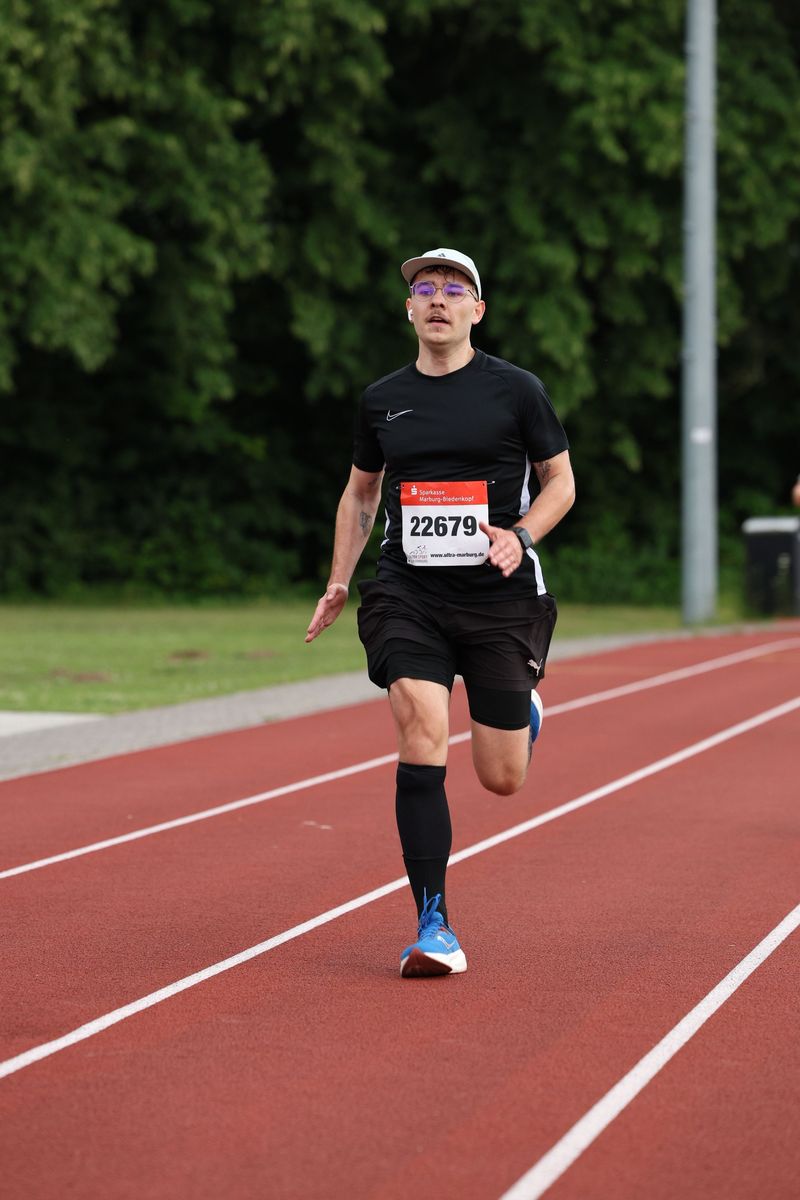 Lucas läuft allein auf einer roten Tartanbahn, auf der Startnummer steht 22679